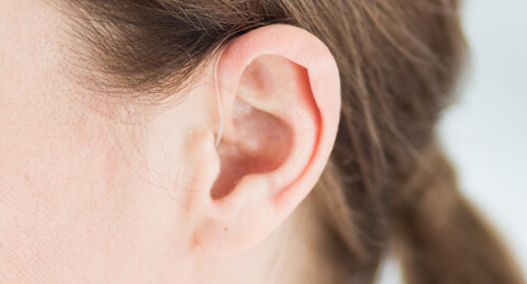 Eine Frau mit einem Hinter-dem-Ohr Hörgerät